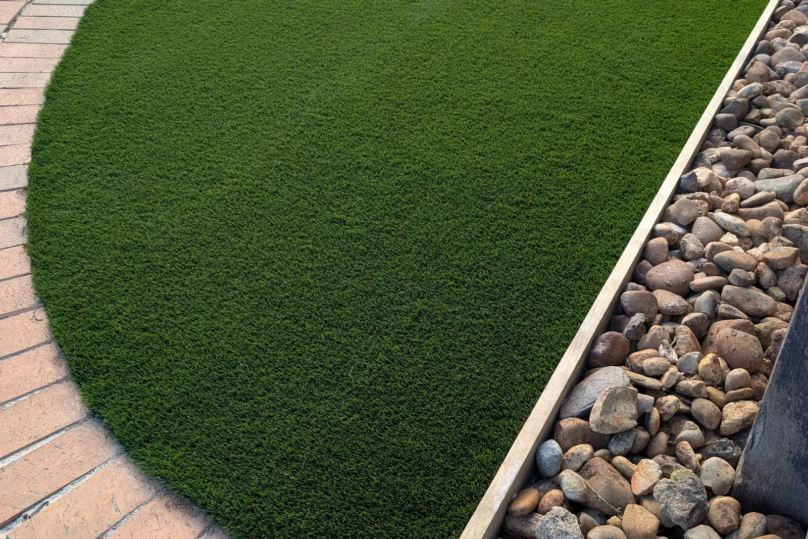 Finished curved lawn beside a landscaped rock garden border