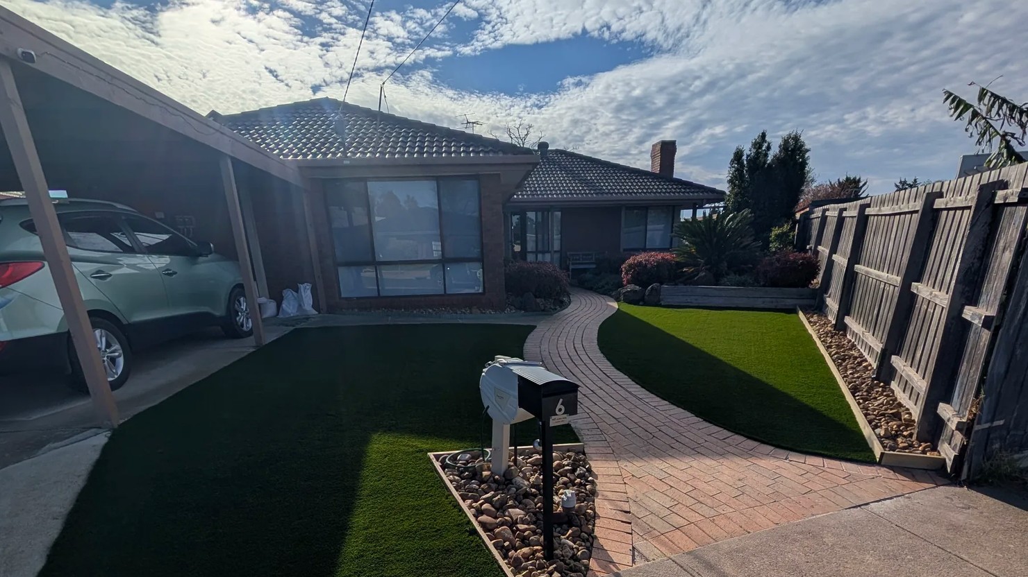 Front yard transformed with new turf and a curved brick path by Bastiano Landscaping