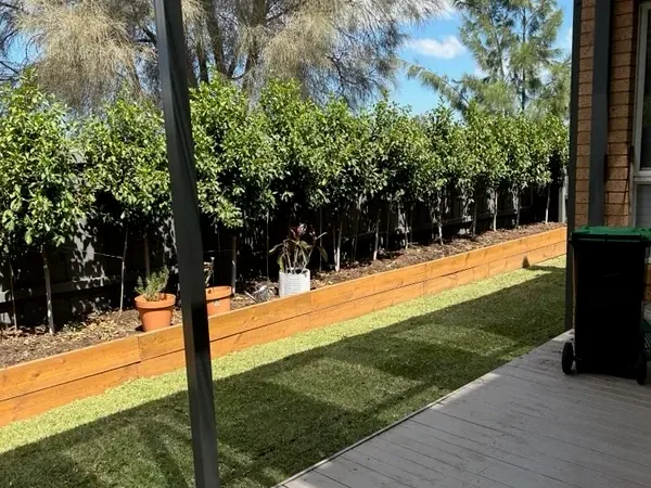 Synthetic turf strip between a covered deck and a sleeper garden bed