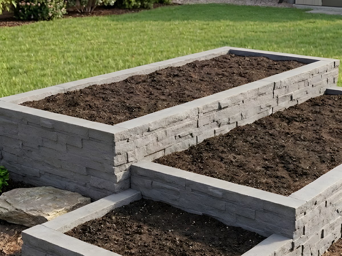 Terraced grey block retaining walls forming raised garden beds beside a new lawn